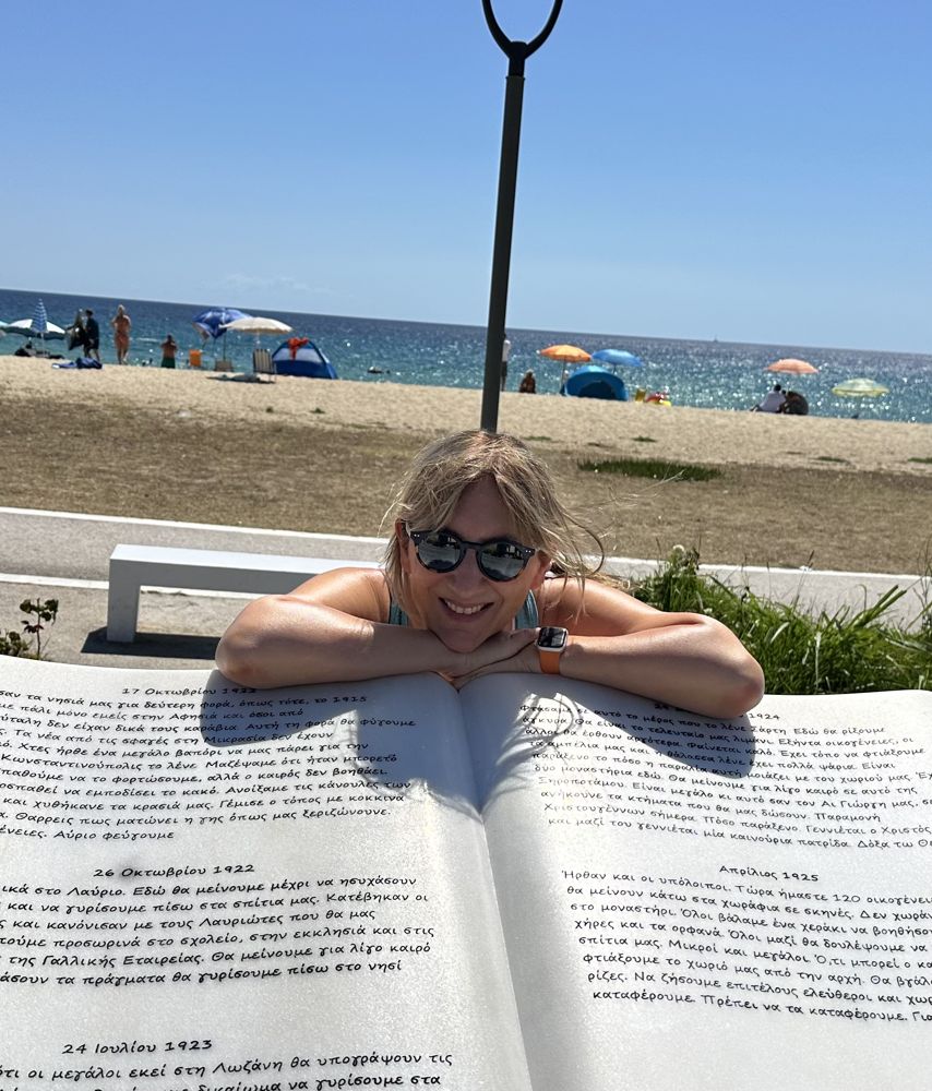 Petra lehnt lachend auf einem großen Stein-Buch am Strand